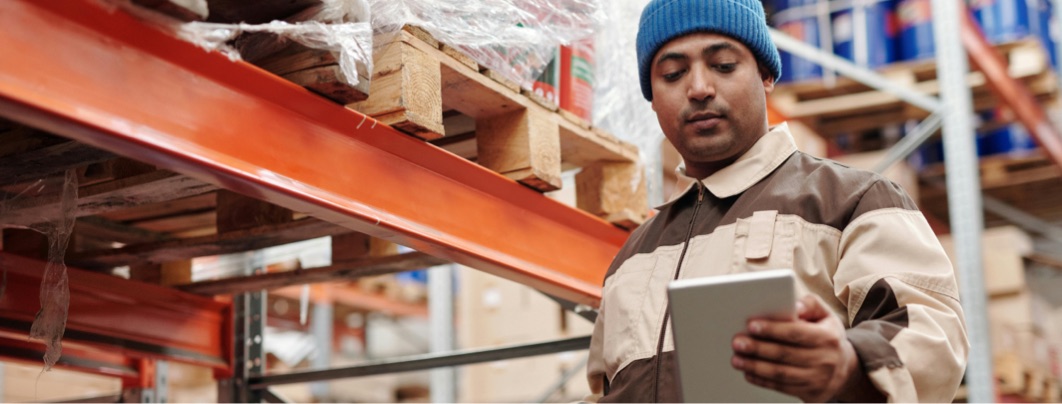 man wearing a beanie looking at a list in a warehouse